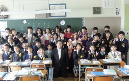市長が卒業生する小学生達と、黒板の前に集合して記念撮影する写真