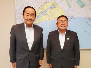 大きな地図が掲示された壁の前で、苫小牧市の岩倉博文市長と市長が並んでいる写真
