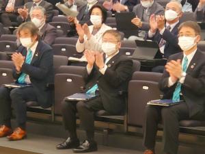 会場の椅子に座り拍手をする様子の市長と関係者たちの写真