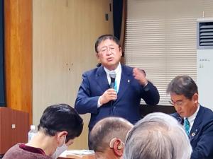 市長と語ろうタウンミーティングが開催されている会場で、関係者や参加者が座っている前で右手にマイクを持ち話をしている市長の写真