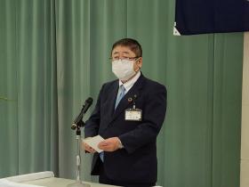 市長が緑色の幕を背景に立ち、閉所式において、あいさつを述べている写真