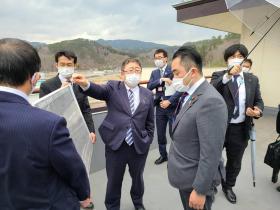 市長が吉川赳内閣府大臣政務官兼復興大臣政務官に他の市職員が広げた地図を指さしながら、復興状況について説明している写真