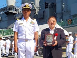 真っ白な制服を着た自衛隊員の方とスーツを着て胸章をつけ盾を持った市長の記念写真