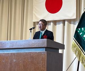 国旗や校旗が設置されたステージの檀上で挨拶を行っている市長の写真