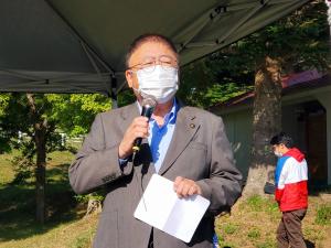 テントの下で左手に紙、右手にマイクを持ち話をする市長を写した写真