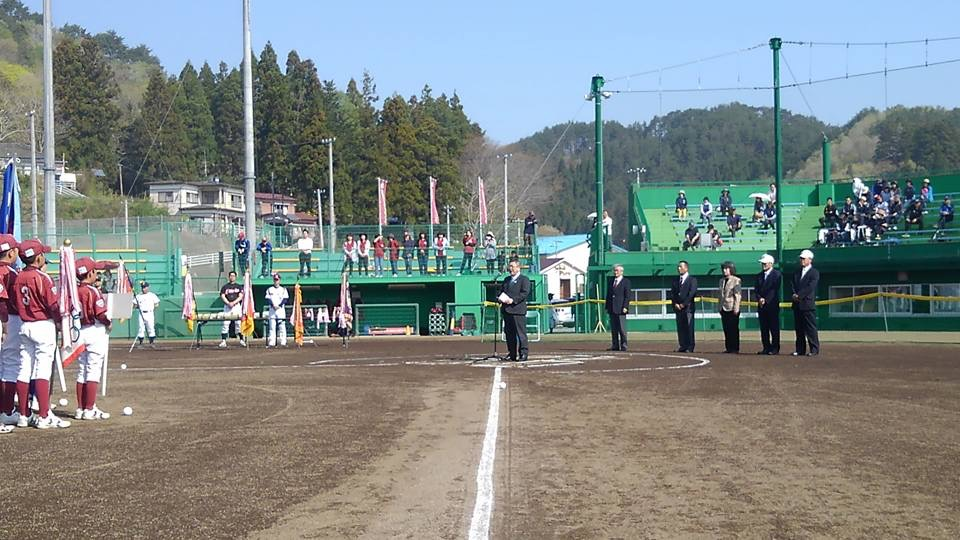 野球場のホームベースに置かれたスタンドマイクに向かい話をする様子の市長の写真