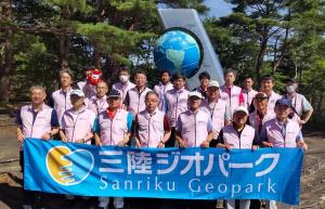 地球をモチーフにしたモニュメントの前で20名程の関係者が3列に並び、最前列に並んだ方々が三陸ジオパークの横断幕を持っている集合写真