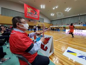 岩手ビッグブルズのユニフォームを着た市長がバスケットB3リーグの試合をコートサイドで応援している写真