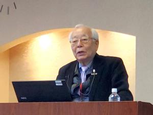 NPO法人日本水フォーラム代表理事の竹村幸太郎さんが演台でノートパソコンを見ながら講演している写真