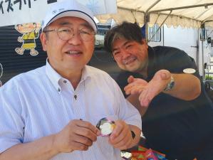 タープテントの中にいる白いシャツに白い帽子をかぶった市長と、黒いシャツを着た男性の写真