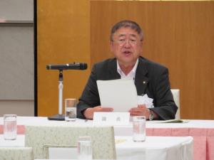 マイクが置かれた席につき、両手で資料を持って話をする市長の写真