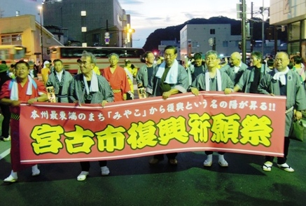 半被をきた男性達が「本州最東端のまち「みやこ」から復興という名の陽が昇る!!宮古市復興祈願祭」と書かれた横断幕を持っている写真