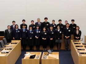 市議会議場内で市長と議会に参加した16人の高校生と教員の方が整列して撮影した写真