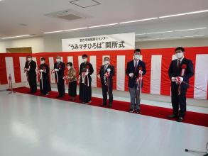 紅白の幕で飾られた開所式で市長の他、関係者の方々他7人で紅白のテープカットをした写真