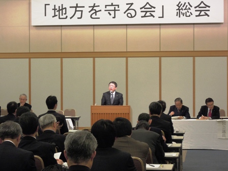 「地方を守る会」総会と書かれた横断幕がある室内に演壇の前で話している市長と参加者が話を聞いている写真