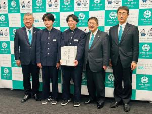 宮古市のバックパネルをバックに新里中学校の生徒2名が能登半島地震災害義援金の箱を持って市長と関係者の方2名にはさまれて記念撮影をしている写真