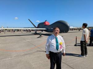 青空の下、自衛隊の航空機を背景にして、市長を撮影した写真