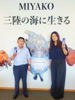 「MIYAKO 三陸の海に生きる」と書かれたパネルの前で、飲料水を手に持った市長と大沼陽さんが映っている写真