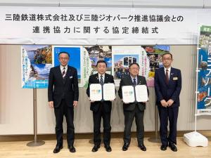 「三陸鉄道株式会社及び三陸ジオパーク推進協議会との連携協力に関する協定締結式」と書かれた横幕やポスターが貼られた前で、代表の男性と市長が両手で締結書を持ち、2名の関係者が左右に立ち横一列に並んでいる写真