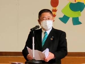 スタンドマイクの前で式辞用紙を両手で広げ話をしている様子の市長の写真