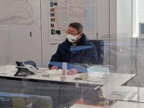 避難訓練で固定電話が置かれた長机の前に市長が資料を片手に持ち着席をしている訓練の様子の写真
