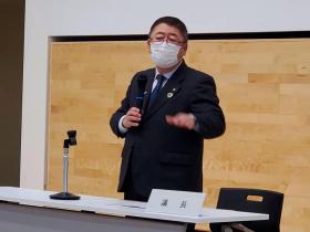 市長が議長と書かれた卓上プレートの席で立ち、来年度の事業計画を述べている写真