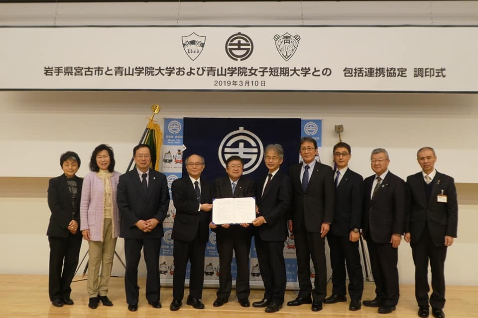 協定書を一緒に持つ市長と2名の男性を中心に、7名の関係者の方々が横一列に並んでいる記念写真