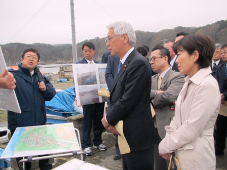 田老地区で写真パネルを持ちながら説明をする市長と、パネルを見ながら話を聞く関係者の写真