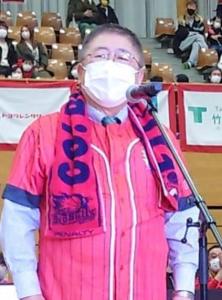 市長が岩手ビッグブルズの赤のユニフォームを着て、赤のタオルを首からかけてあいさつをしている写真