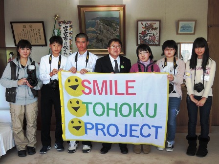 「SMILE TOHOKU PROJECT」と書かれた横断幕を持つ市長と6名の中学生たちの記念写真
