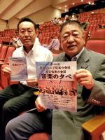 客席に座り、「音楽の夕べ」のパンフレットを手に持っている市長と関係者の写真