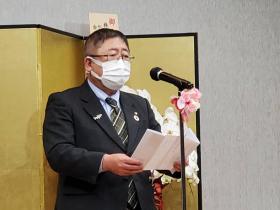 会場の金屏風の前で、市長が受賞のお祝いの言葉を述べている写真