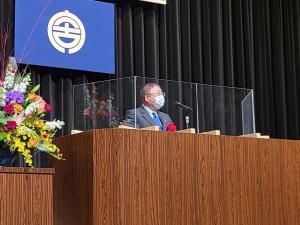 クリアパネルが置かれた演台で、話をする様子の市長の写真