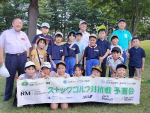 市長と参加した小学生たちが集合して、前列の小学生が「スナッグゴルフ対抗戦 予選会」と書かれた横断幕を持ち、撮影した写真