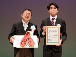 感謝状を見せている中澤星音さんと、しおんさんが駅伝で使用し寄贈したシューズを市長が持って2人で記念撮影をしている写真