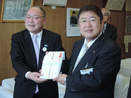 寄附金の封筒を一緒に持つ市長と男性の記念写真