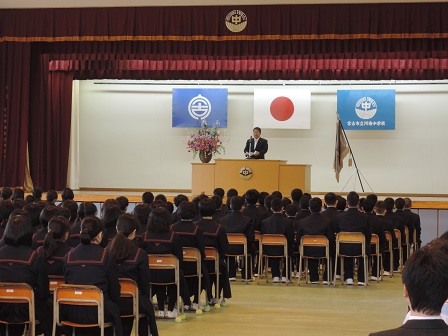 会場に並べられた椅子に座る制服を着た中学生たちと、舞台上の演台のマイクに向かい話をする市長の写真