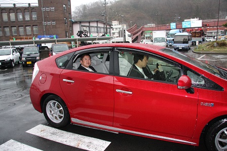 赤い車の後部座席に乗る市長を写した写真