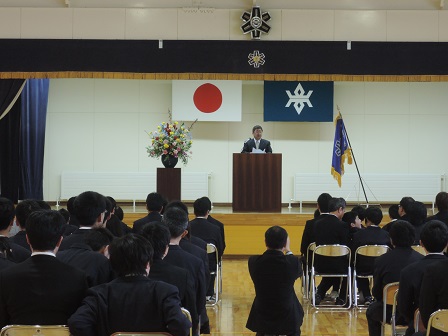 会場に並べられたパイプ椅子に座る新入生たちと、舞台上の演台のマイクに向かい話をする市長の写真