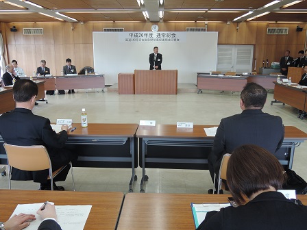 コの字に並べられた長机の席に着く関係者の方々と、会場の前方で演台に置かれたマイクに向かい話をする市長の写真
