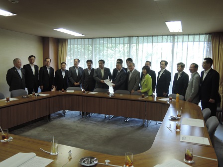 要望書を一緒に持つ男性2名と、14名の男性、1名の女性が立って並んでいる記念写真