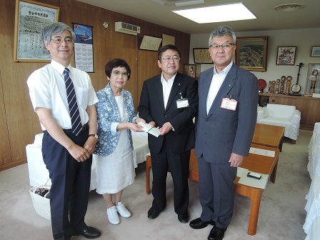 目録を一緒に持つ市長と女性を中心に、男性2名が並んでいる記念写真