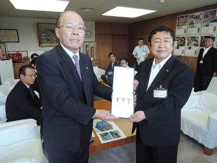 細長い紙のようなものを一緒に持つ市長と男性の記念写真