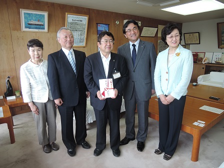 目録を持つ市長を中心に、女性2名と男性2名が立って並んでいる記念写真