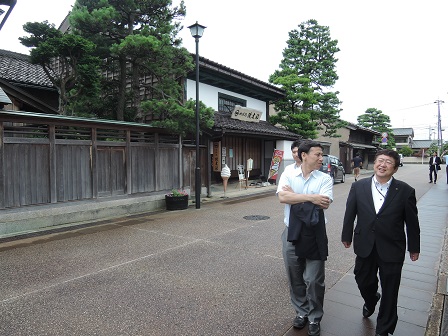 道路脇を並んで歩く男性と市長の写真