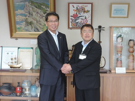 両手で握手をする山本市長と群馬県桐生市の亀山豊文市長の写真