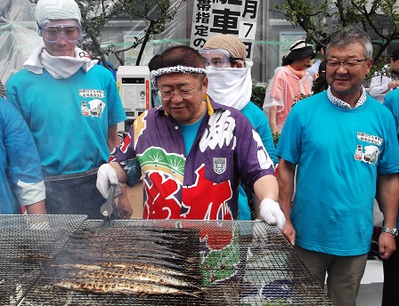 網に乗せられたサンマをトングでつかんでいる様子の市長の写真