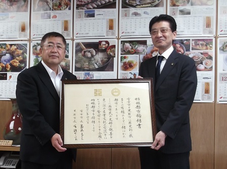 締結書の額縁を一緒に持つ市長と青森県黒石市の高樋憲市長の記念写真