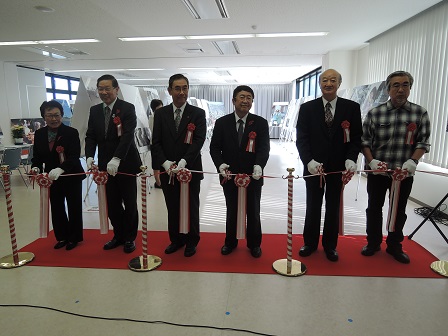レッドカーペットの上に立ち、テープカットをする様子の市長と5名の関係者たちの写真