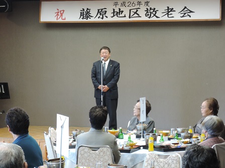 「平成26年度 祝 藤原地区敬老会」と書かれた横断幕の下で、スタンドマイクに向かい話をする市長の写真
